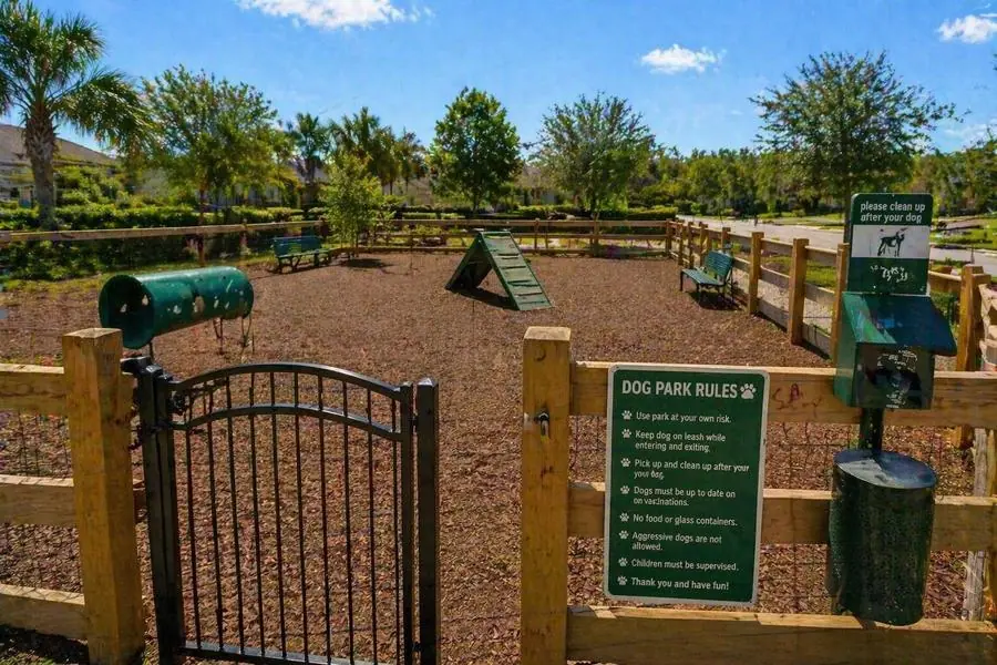 Fenced community dog park with agility equipment and waste station